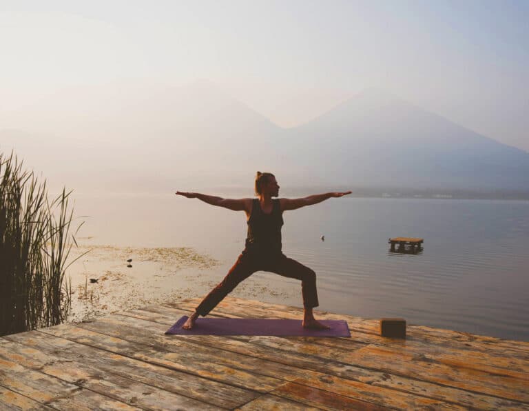 Yoga retreat Guatemala Lake Atitlan warrior 2 on dock by volcanos